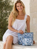 Woman in a white dress holding a blue floral bag outdoors.