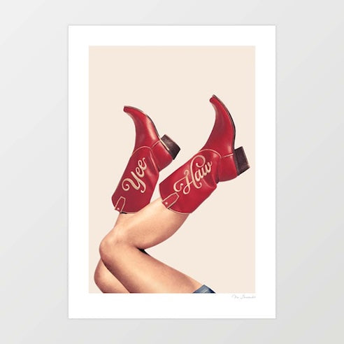 These Boots Yeehaw Rustic Red and Neutral art print — bare tanned legs kicked up wearing deep cherry red mid-calf cowboy boots with cream cursive Yee Haw script lettering across the shaft against a soft warm cream neutral background, cowgirl core western art print for Nashville bachelorette ranch Airbnb hotel lobby and rodeo interiors