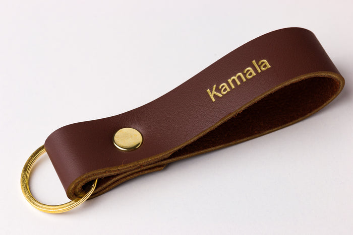 Close-up of thick brown leather loop keychain with brass snap and ring — sturdy everyday carry key fob.