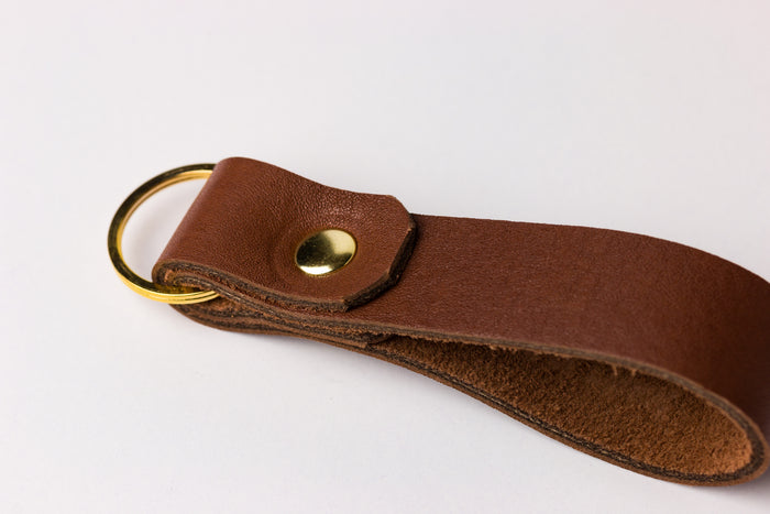 Side profile of thick leather loop keychain showing layered leather edge and brass rivet detail.