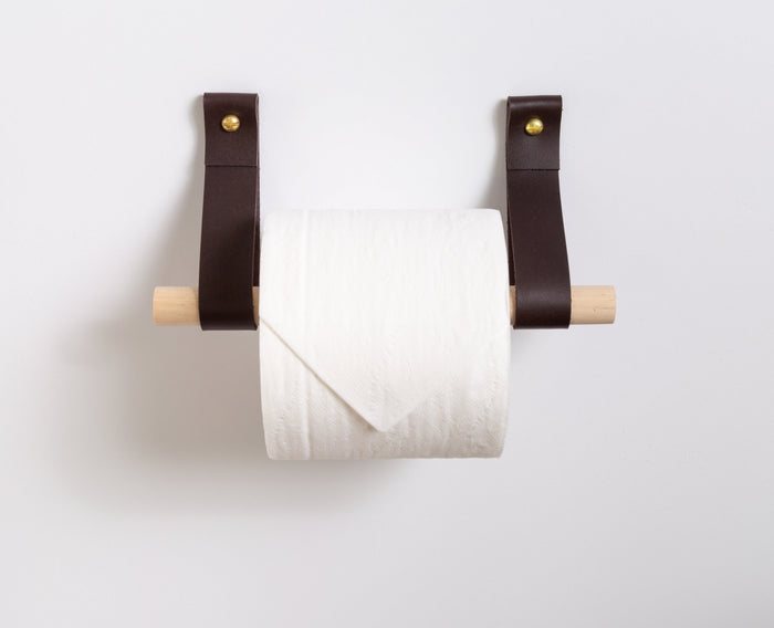 Elegant handmade leather strap toilet paper holder with rich walnut dowel for minimalist home decor.