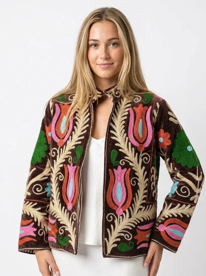 Woman wearing a colorful embroidered jacket on a white background