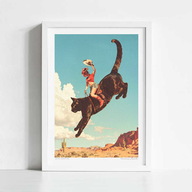 Yeehaw Rodeo Cat Cowgirl art print framed view — giant black cat with cowgirl rider leaping across blue desert sky with billowing clouds, surreal pop surrealism Western cat art for Nashville bachelorette suites and cowgirl-core interiors
